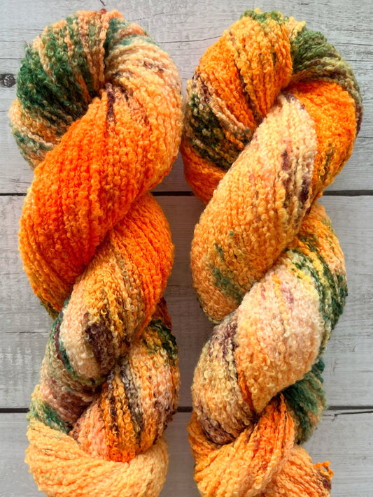Håndfarvet garn i Merino Bouclé uld. Dette håndfarvede Merino Bouclé er farvet med smukke nuancer af orange, grøn og rosa
