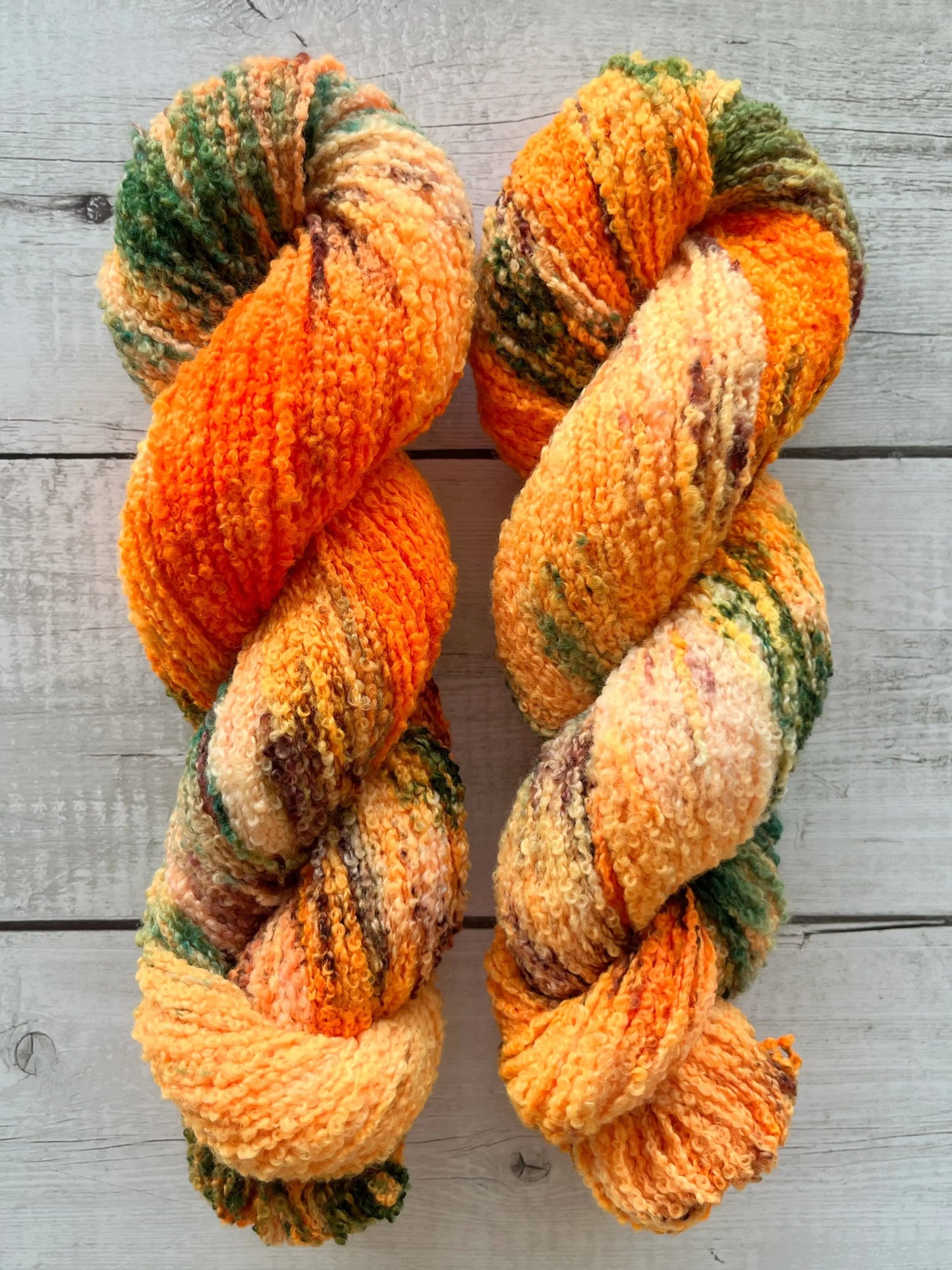 Håndfarvet garn i Merino Bouclé uld. Dette håndfarvede Merino Bouclé er farvet med smukke nuancer af orange, grøn og rosa