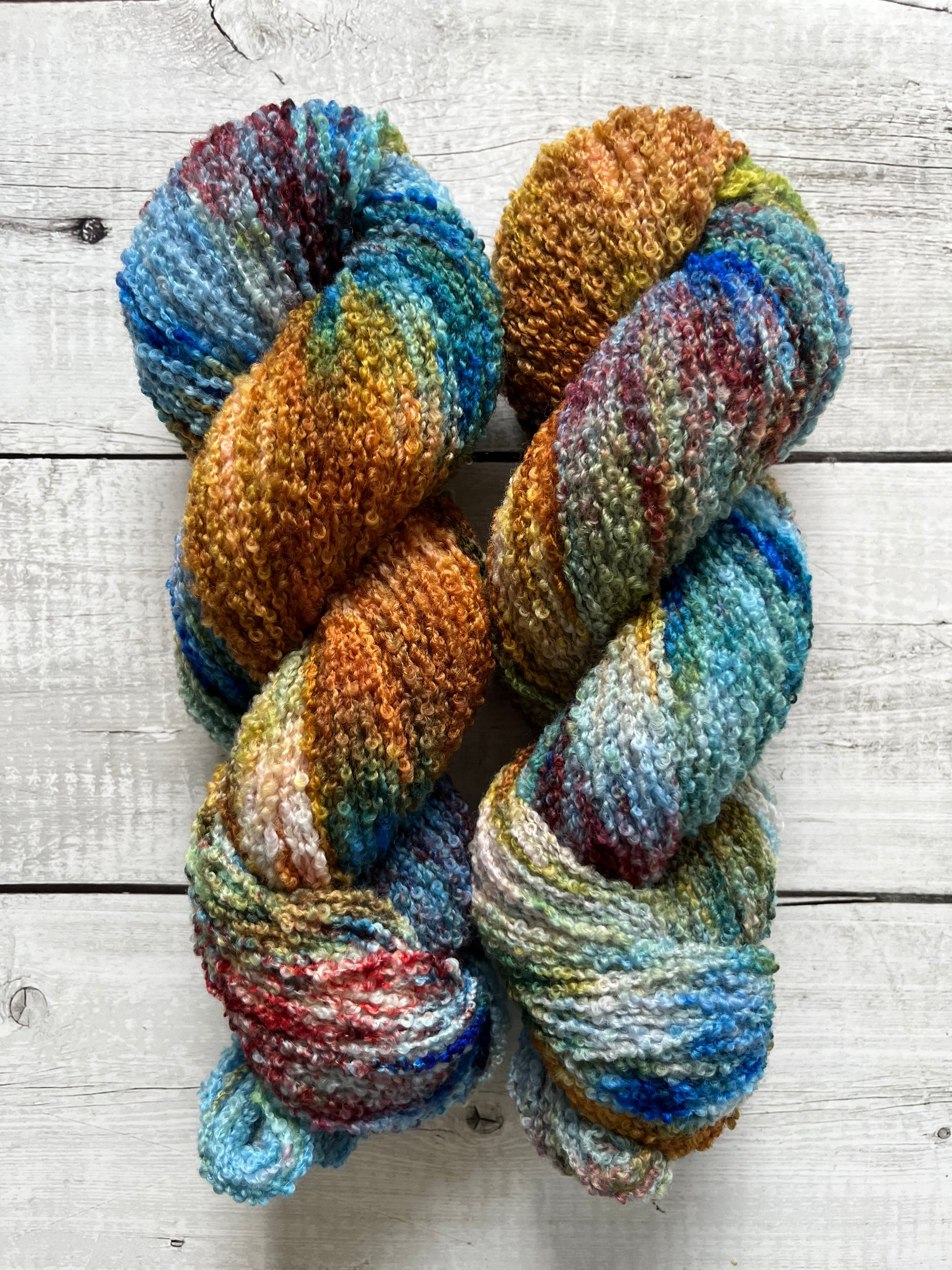 Håndfarvet garn i Merino Bouclé uld. Dette håndfarvede Merino Bouclé er farvet med smukke nuancer af kobolt blå, gylden brun og lilla rosa