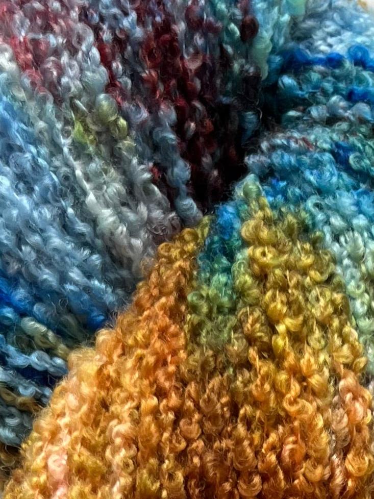 Håndfarvet garn i Merino Bouclé uld. Dette håndfarvede Merino Bouclé er farvet med smukke nuancer af kobolt blå, gylden brun og lilla rosa