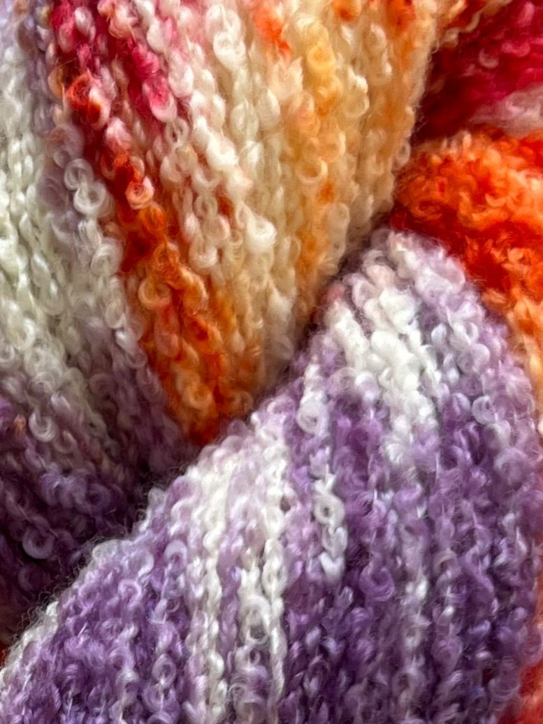 Håndfarvet garn i Merino Bouclé uld. Dette håndfarvede Merino Bouclé er farvet med smukke nuancer af lilla, pink og orange