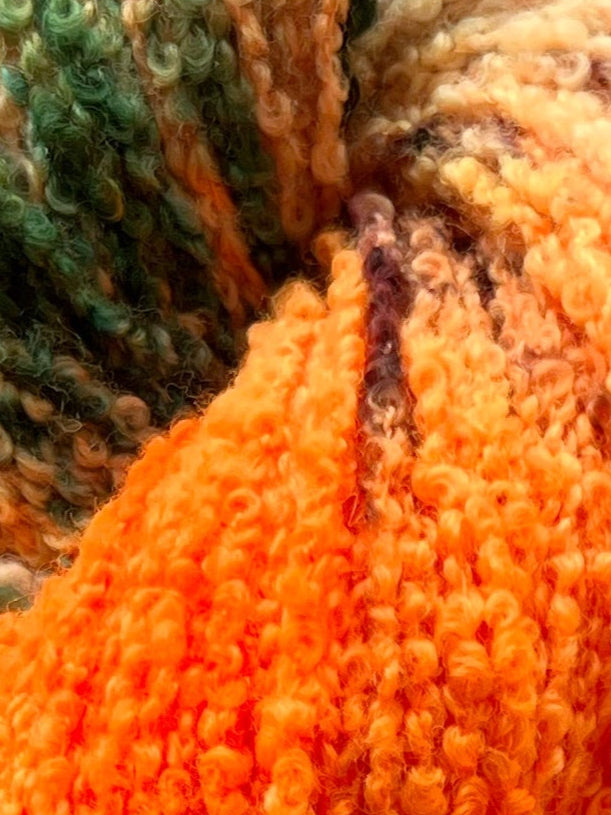 Håndfarvet garn i Merino Bouclé uld. Dette håndfarvede Merino Bouclé er farvet med smukke nuancer af orange, grøn og rosa