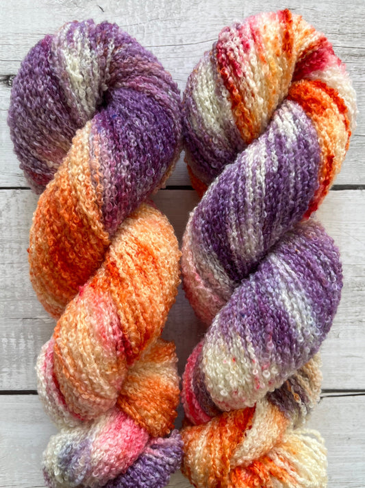 Håndfarvet garn i Merino Bouclé uld. Dette håndfarvede Merino Bouclé er farvet med smukke nuancer af lilla, pink og orange